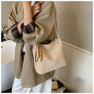 Detail view of leopard print bucket bag with wooden bead tassel and long shoulder strap