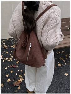 Détail d'un sac à dos en daim marron foncé avec forme triangulaire unique et zips argentés
