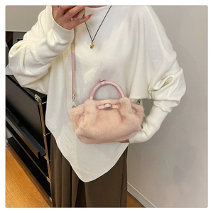 Nahaufnahme einer hellrosa Plüsch-Handtasche mit Ledergriff und silberner Metallschnalle