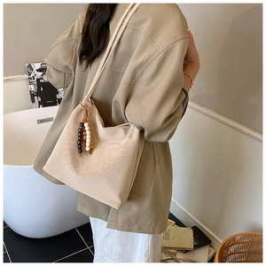 Detail of minimalist beige hobo bag showing soft leather texture and colorful wooden beads