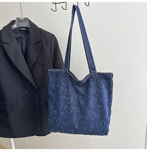 Detail view of deep blue denim tote bag with hand-drawn heart patterns and premium stitching