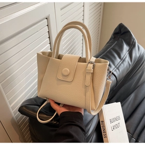 Détail du sac seau crème avec texture litchi et fermoir magnétique rond élégant