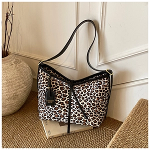 Detail of leopard print tote bag with black leather straps and golden metal hardware