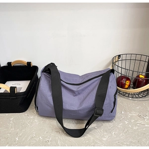 Detail view of a lavender nylon sports travel bag with adjustable black shoulder strap