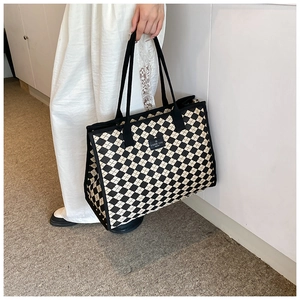 Detailed side view of large checkered canvas tote bag with black logo label and handles