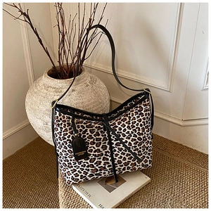 Detail of leopard print hobo bag with black leather shoulder strap and fashion hangtag