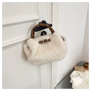 Detail der cremefarbenen Kunstfelltasche mit braunen Ledergriffen und silberner Schnalle