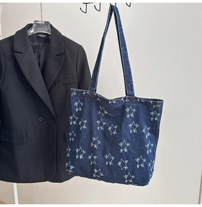 Detail of dark blue denim tote bag with star embroidery hanging next to a black blazer