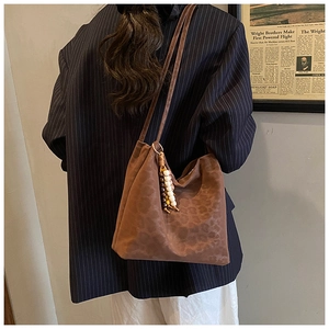 Close-up of brown suede leopard print bucket bag with vintage wooden bead tassel detail