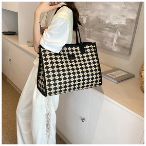Close-up of black and white harlequin canvas tote bag with shoulder strap and chic logo