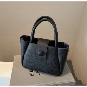 Détail d'un sac à main noir en cuir grainé litchi avec structure trapèze et double poignée