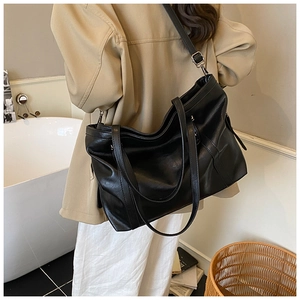 Détail d'un grand sac cabas noir avec bandoulière réglable et texture en similicuir souple