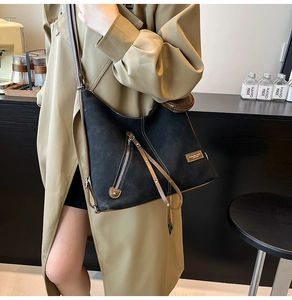 Detail of black frosted tote bag with caramel leather trim and metal zipper accents
