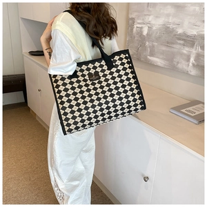 Close-up of checkered canvas tote bag with I LOVE YOU HAPPY label and sturdy black handle
