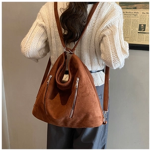 Détail arrière d'un sac à dos vintage en daim marron avec fermetures éclair argentées