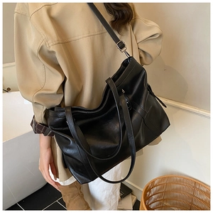 Détail d'un grand sac cabas vintage noir avec bandoulière réglable porté par un mannequin