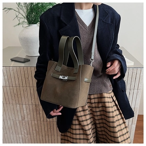 Detail of olive green suede bucket bag with silver hardware lock and dual handles