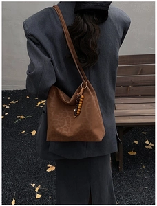 Detailed close-up of a leopard print suede hobo bag with ethnic wooden bead accents for autumn