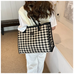 Close-up of black and white checkered canvas tote bag with I LOVE YOU HAPPY leather patch