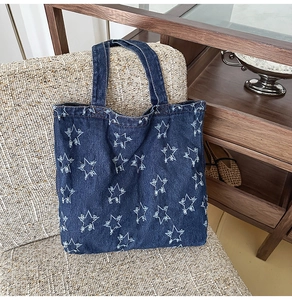 Detail of blue denim tote bag featuring frayed white star patterns and vintage texture