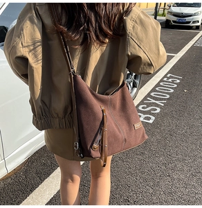 Macro shot of dark brown suede hobo bag with zip details and leather shoulder straps