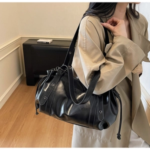Detail of black leather shoulder bag with cloud-like pleats and metallic rivets on strap