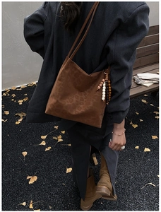 Detail of leopard print suede shoulder bag with decorative wooden beads in autumn street setting