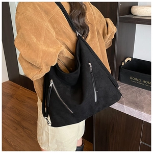 Détail d'un sac hobo noir mat avec fermetures éclair argentées vue sous un angle latéral