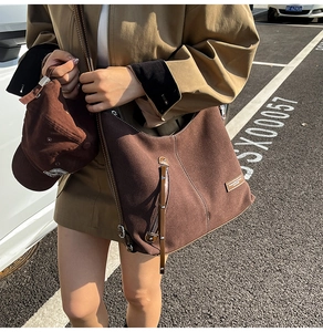 Close-up of deep brown suede hobo bag with contrast stitching and metal zipper detail
