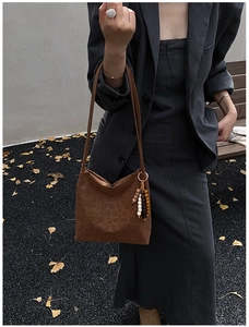 Brown suede leopard print bucket bag with ethnic wooden bead charm worn by a model outdoors