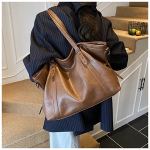 Grand sac cabas rétro marron à clous étoiles porté par un mannequin en costume chic