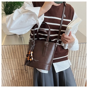 Detail einer dunkelbraunen Vintage-Eimertasche mit Holzperlenquasten und Lederstruktur
