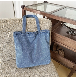 Detail of blue denim tote bag with white heart patterns on a stylish woven chair