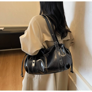 Close-up of the glossy black leather tote bag featuring drawstring detail and metal eyelets
