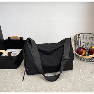 Detail of a black large-capacity crossbody bag made of durable pleated nylon fabric