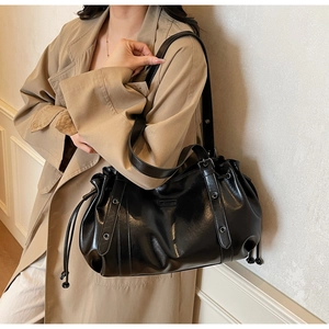 Detail of black glossy leather tote bag with pleated drawstring and silver studs