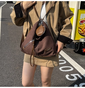 Detail of dark brown canvas triangular backpack with silver zipper and leather strap