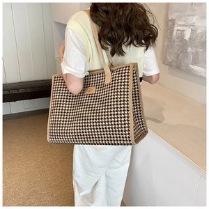 Back view of a model carrying the large houndstooth tote bag in a minimalist setting