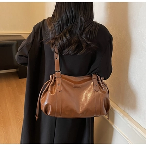 Detail of vintage brown leather shoulder bag with adjustable straps and side drawstring