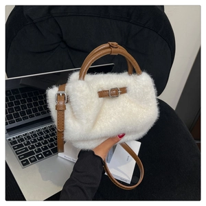 Detail der cremeweißen Plüschhandtasche mit braunen Ledergriffen und Silberbeschlägen