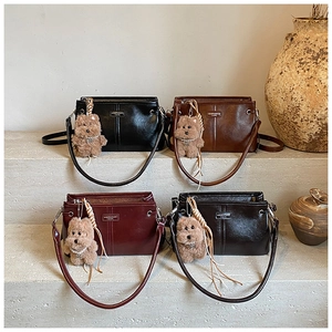 Détail de sacs bandoulière vintage en quatre couleurs avec plaque métal et charm ours