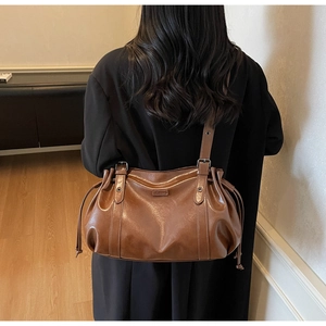 Detail view of large brown shoulder bag with drawstring texture and polished leather finish