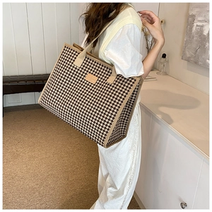 Detail view of the large capacity houndstooth tote bag worn by a model in a modern room