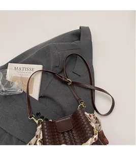 Detail of dark brown woven bucket bag with floral scarf on a grey blazer outfit