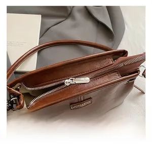Gros plan d'un sac à main en cuir marron avec fermeture éclair argentée et étiquette de marque
