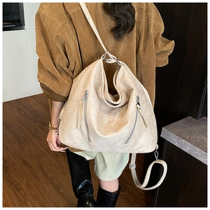 Détail d'un grand sac bandoulière beige en daim mat avec deux fermetures éclair verticales