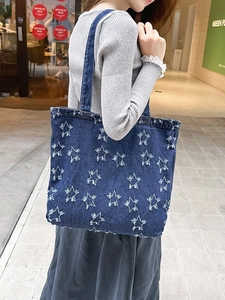 Vintage denim tote bag with frayed star patterns and long shoulder straps for daily use