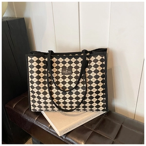 Detailed macro view of the checkered canvas tote bag with black strap and logo patch