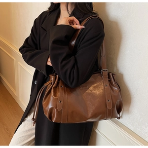 Détail d'un sac bandoulière vintage marron avec cordon de serrage et œillets métalliques