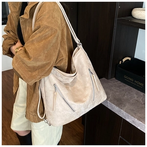 Détail du sac à épaule en daim beige avec fermetures éclair argentées et tissu